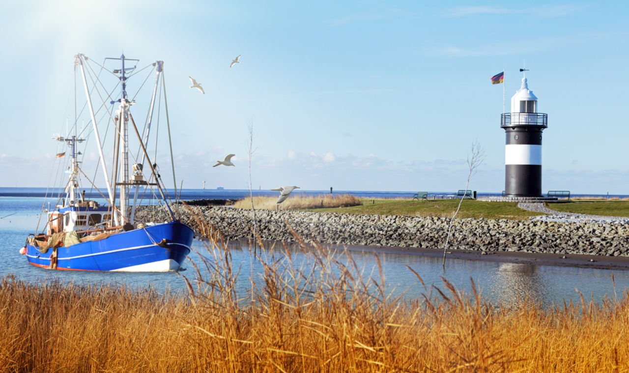 Fischerboot neben einem Leuchtturm in Cuxhaven, Deutschland